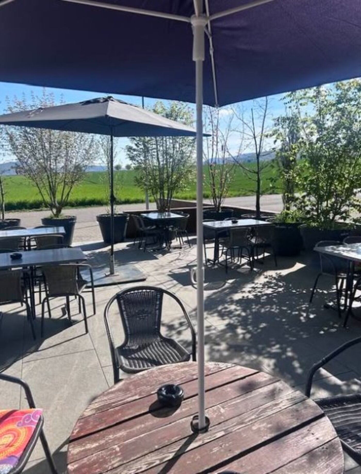Terrasse extérieure ombragée du Béa-Ba avec vue sur la campagne jurassienne